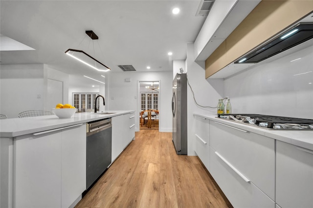 kitchen with sink, hanging light fixtures, light hardwood / wood-style flooring, white cabinetry, and stainless steel appliances