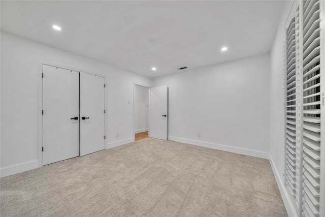 unfurnished bedroom with light colored carpet and a closet