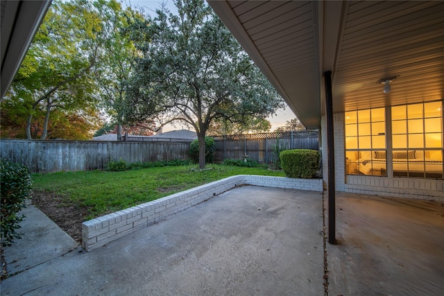 patio terrace at dusk featuring a yard