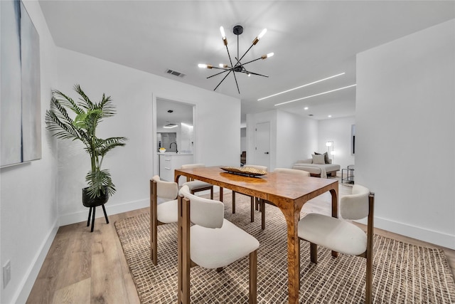 dining area featuring sink, an inviting chandelier, and light wood-type flooring