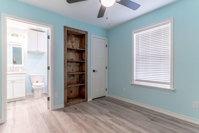 unfurnished bedroom featuring connected bathroom, sink, light hardwood / wood-style flooring, and ceiling fan