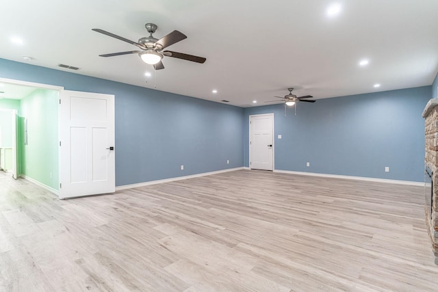 unfurnished living room featuring ceiling fan, a fireplace, and light wood-type flooring