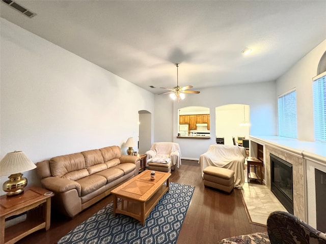 living room featuring hardwood / wood-style flooring, ceiling fan, and a tiled fireplace