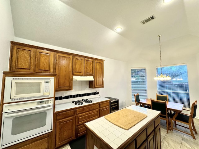 kitchen featuring tile counters, beverage cooler, hanging light fixtures, a chandelier, and white appliances