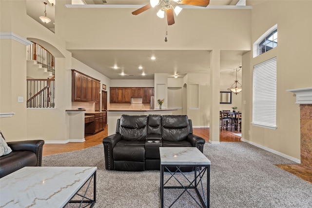 carpeted living room with ceiling fan and a towering ceiling