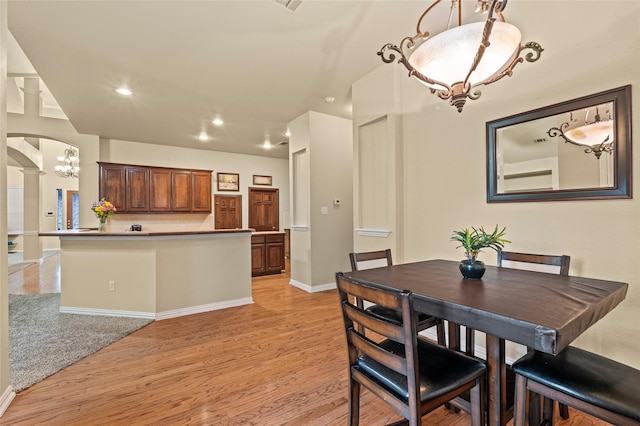 dining room featuring light wood-type flooring and decorative columns