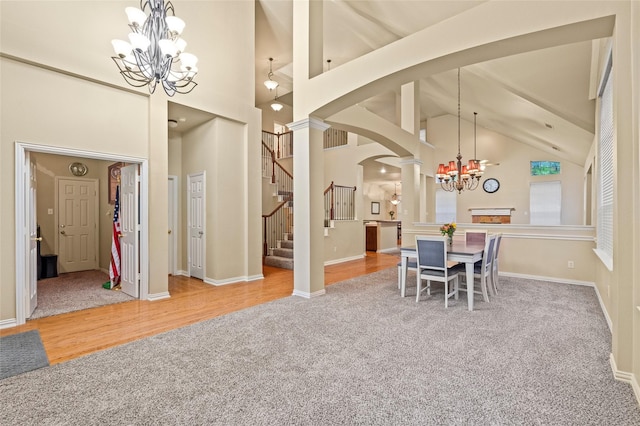 dining room featuring high vaulted ceiling, ornate columns, a notable chandelier, and carpet flooring