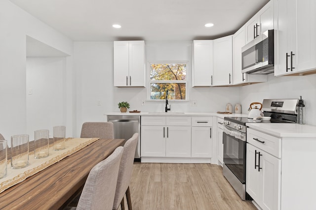 kitchen featuring sink, light hardwood / wood-style flooring, white cabinets, and appliances with stainless steel finishes