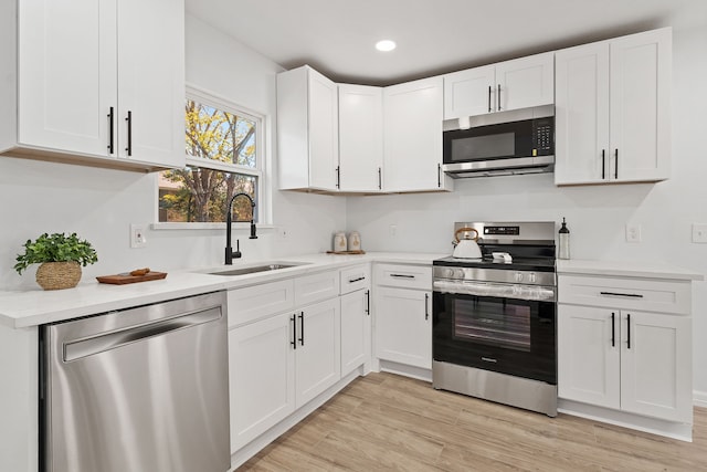 kitchen with light wood-type flooring, white cabinetry, sink, and appliances with stainless steel finishes