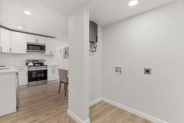 kitchen with light hardwood / wood-style flooring, white cabinets, and stainless steel appliances