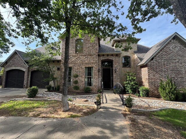117 Woodland Dr, Krugerville, TX 76227 - french country style house with brick siding, a shingled roof, driveway, and a garage