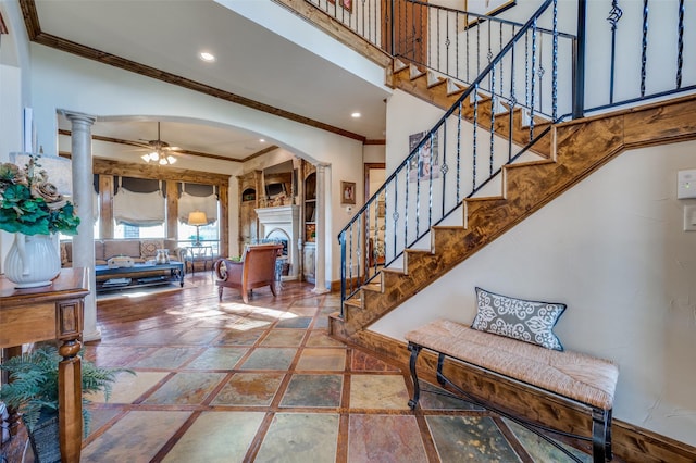 foyer with crown molding, ceiling fan, a high ceiling, and ornate columns