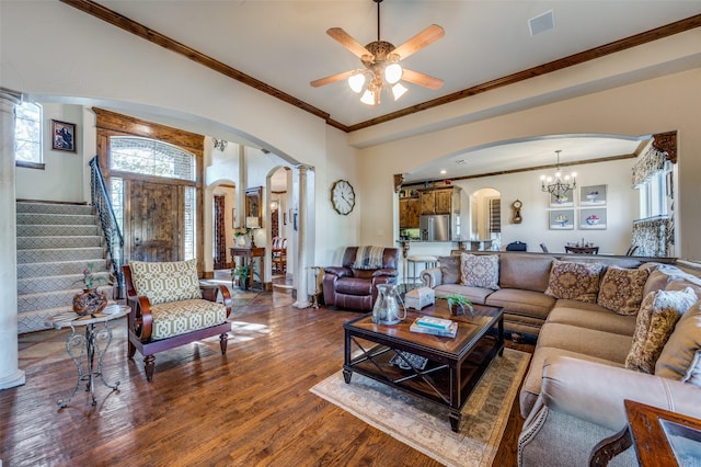 living room featuring ceiling fan with notable chandelier, wood-type flooring, ornamental molding, and decorative columns