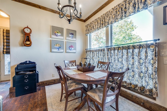 dining area with crown molding, dark wood-type flooring, and an inviting chandelier