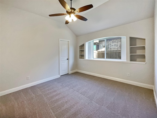 carpeted empty room featuring built in shelves, ceiling fan, and lofted ceiling