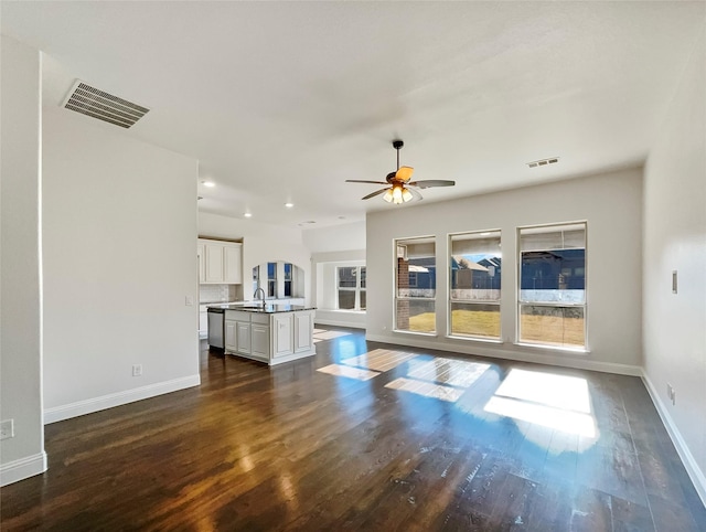 unfurnished living room with ceiling fan, sink, and dark wood-type flooring