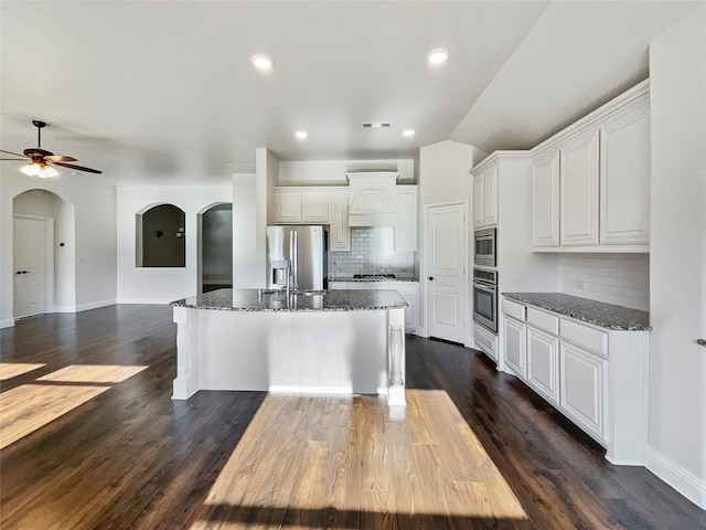 kitchen featuring white cabinets, backsplash, stainless steel appliances, and dark wood-type flooring