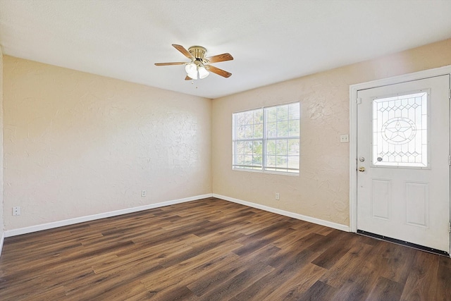 foyer entrance with ceiling fan and dark wood-type flooring