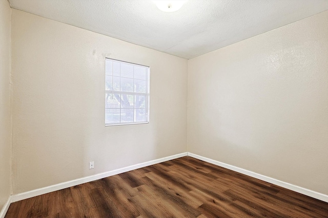 empty room with a textured ceiling and dark hardwood / wood-style floors