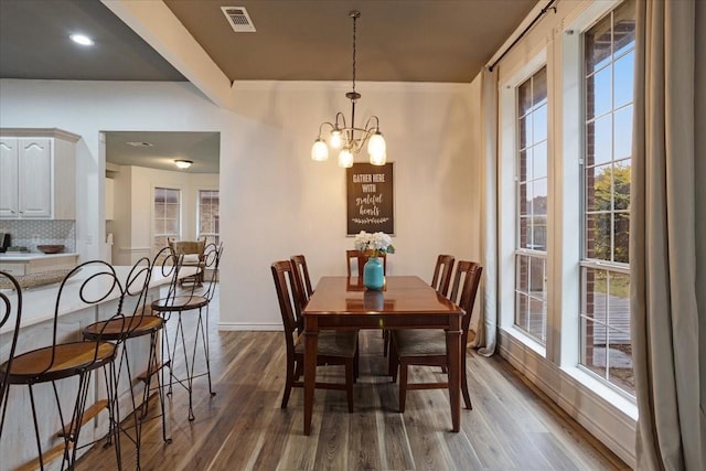 dining area featuring wood-type flooring and a notable chandelier