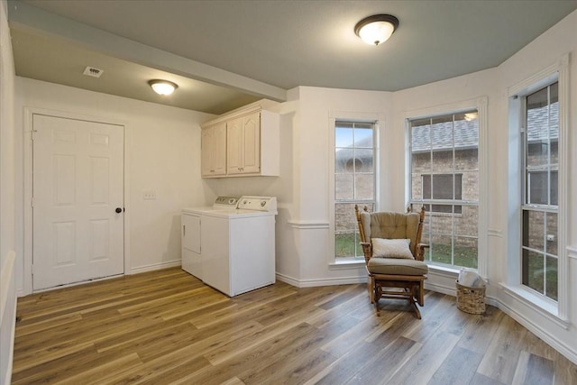 laundry area featuring cabinets, separate washer and dryer, and light hardwood / wood-style flooring