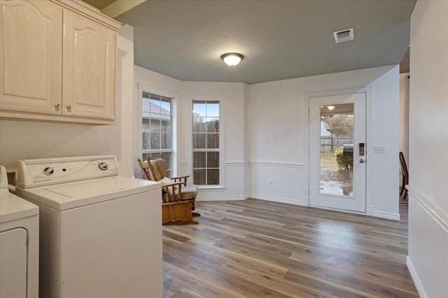 laundry room featuring separate washer and dryer, cabinets, and light wood-type flooring