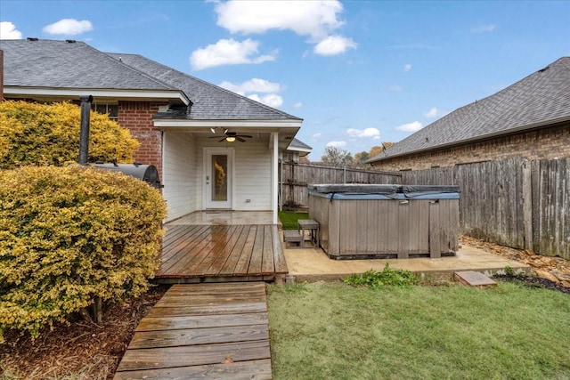 exterior space featuring a lawn, ceiling fan, and a hot tub