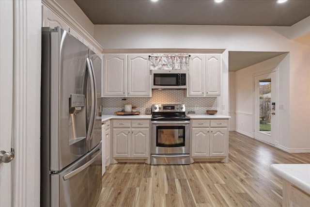 kitchen with tasteful backsplash, white cabinetry, light hardwood / wood-style flooring, and appliances with stainless steel finishes