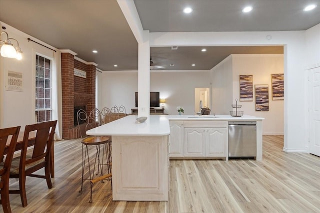 kitchen featuring a center island, light hardwood / wood-style floors, stainless steel dishwasher, and sink