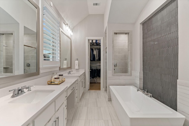 bathroom with vanity, vaulted ceiling, tile walls, tile patterned flooring, and shower with separate bathtub