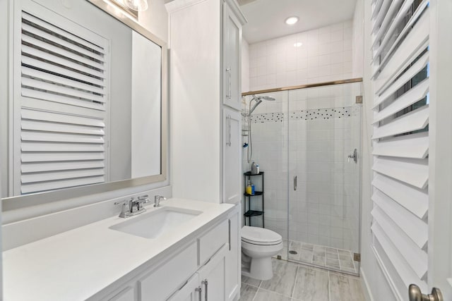 bathroom with vanity, toilet, and a shower with shower door