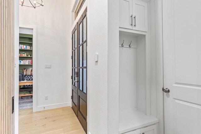 mudroom with a chandelier and light wood-type flooring