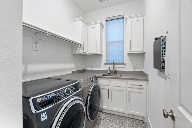 clothes washing area featuring washing machine and dryer, sink, and cabinets