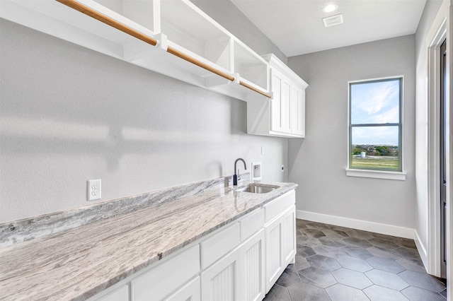 laundry room with sink, cabinets, washer hookup, hookup for an electric dryer, and dark tile patterned flooring