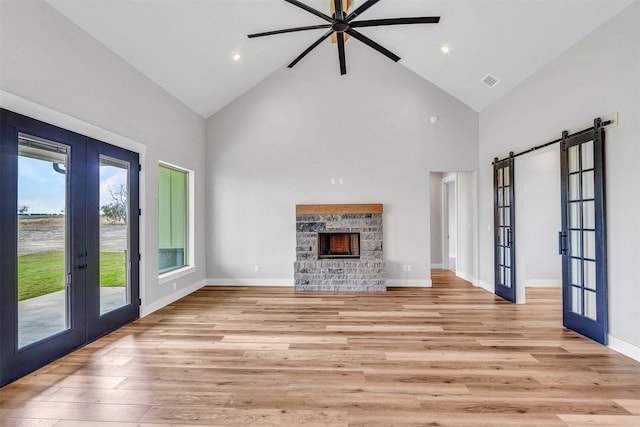 unfurnished living room featuring french doors, light hardwood / wood-style floors, high vaulted ceiling, and ceiling fan