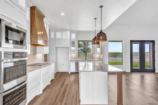 kitchen featuring white cabinets, premium range hood, appliances with stainless steel finishes, and light hardwood / wood-style flooring