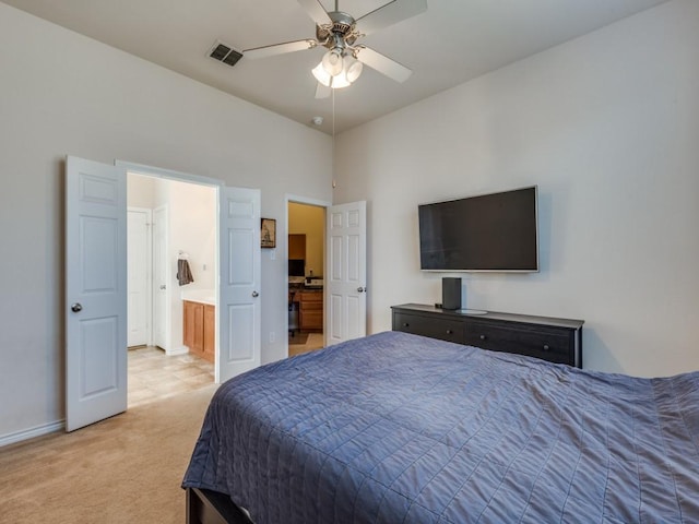 bedroom featuring ceiling fan, light colored carpet, and ensuite bath