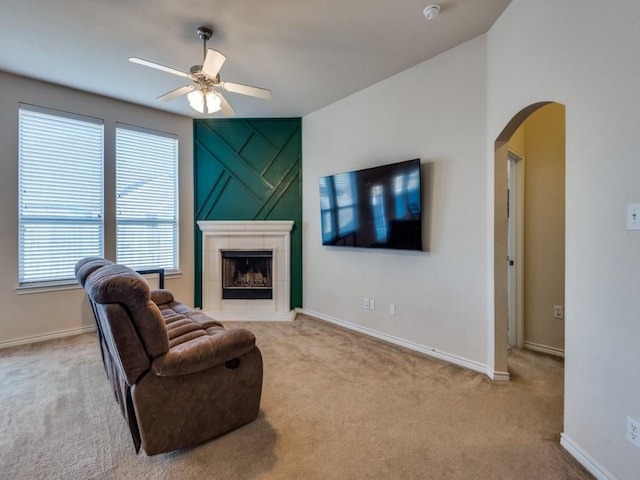 carpeted living room featuring ceiling fan and a tiled fireplace