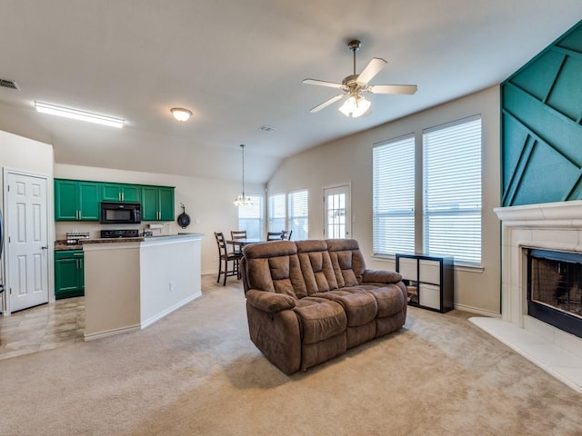 carpeted living room featuring a tiled fireplace, ceiling fan, and vaulted ceiling