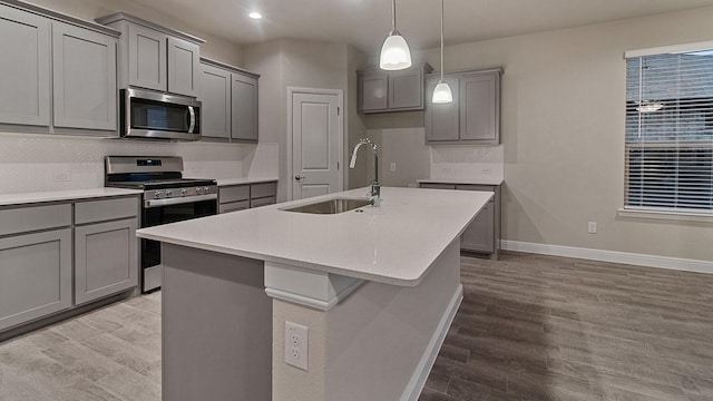 kitchen featuring gray cabinets, a center island with sink, stainless steel appliances, and light hardwood / wood-style floors