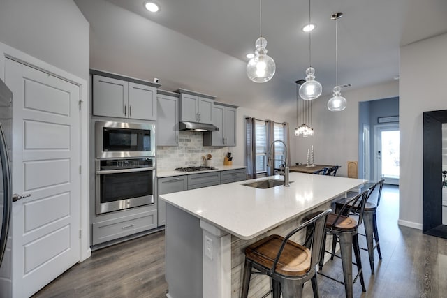 kitchen with sink, decorative light fixtures, gray cabinets, a kitchen island with sink, and appliances with stainless steel finishes