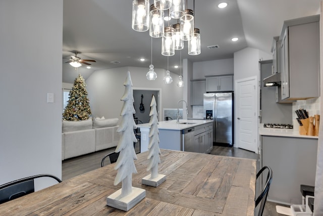 dining room with ceiling fan with notable chandelier, dark wood-type flooring, lofted ceiling, and sink