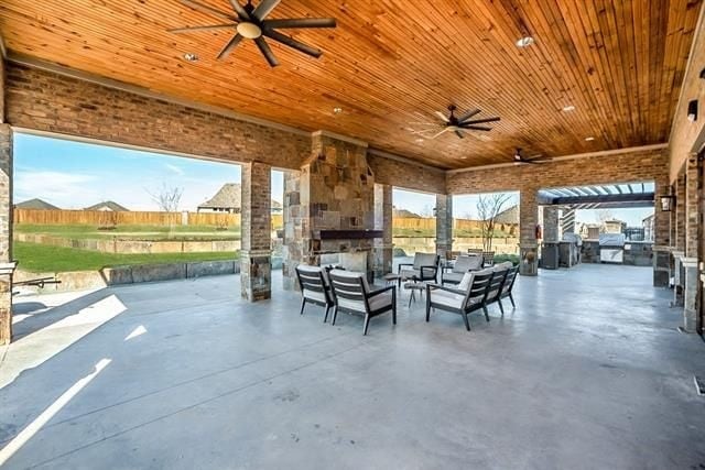 view of patio / terrace with exterior kitchen and an outdoor stone fireplace