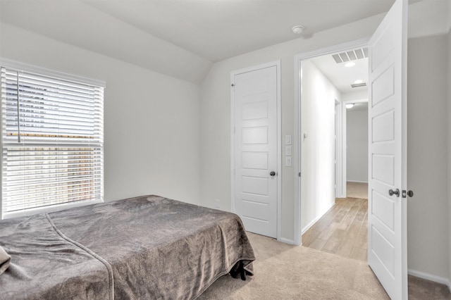 bedroom featuring light hardwood / wood-style floors and vaulted ceiling