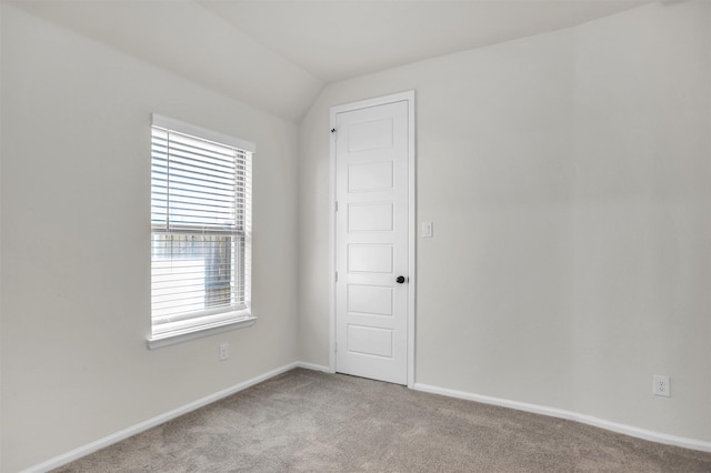 carpeted empty room featuring vaulted ceiling