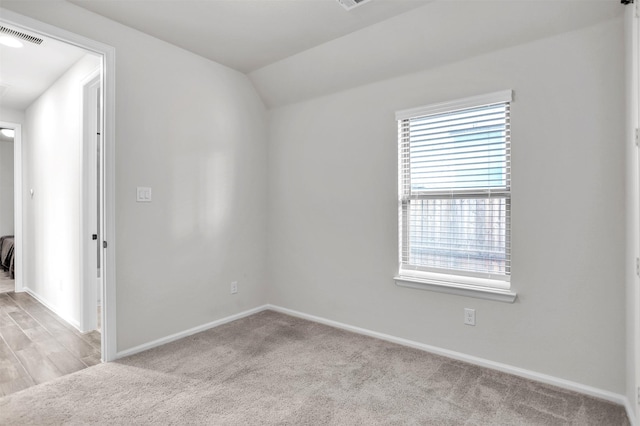 spare room with light colored carpet and lofted ceiling