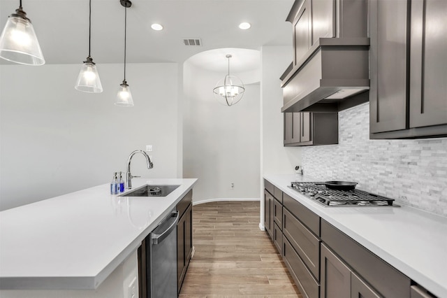 kitchen with sink, stainless steel appliances, a notable chandelier, decorative light fixtures, and light wood-type flooring