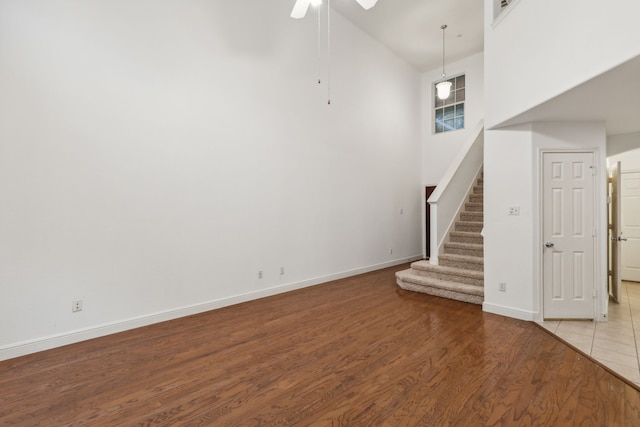 unfurnished living room with hardwood / wood-style flooring, high vaulted ceiling, and ceiling fan