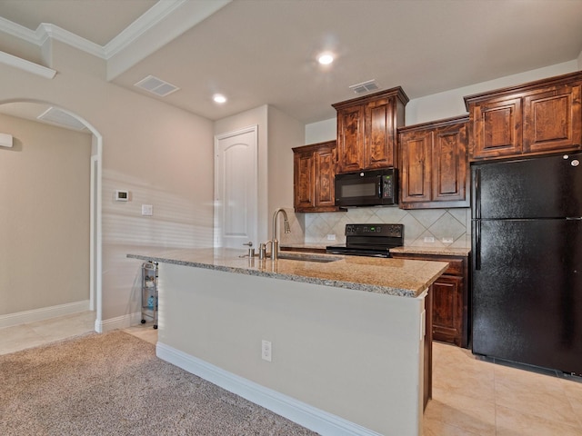 kitchen with black appliances, sink, light tile patterned floors, an island with sink, and tasteful backsplash