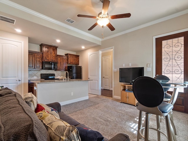 carpeted living room featuring ceiling fan, ornamental molding, and sink